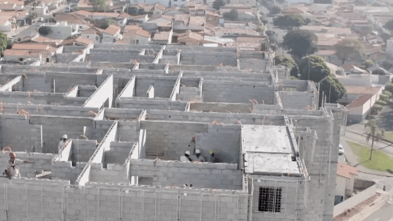 Vista aérea de edifício residencial em alvenaria estrutural durante a montagem da laje pronta no pavimento.